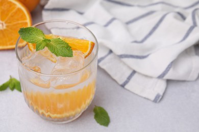 Photo of Refreshing water with orange and mint in glass on light table, closeup. Space for text