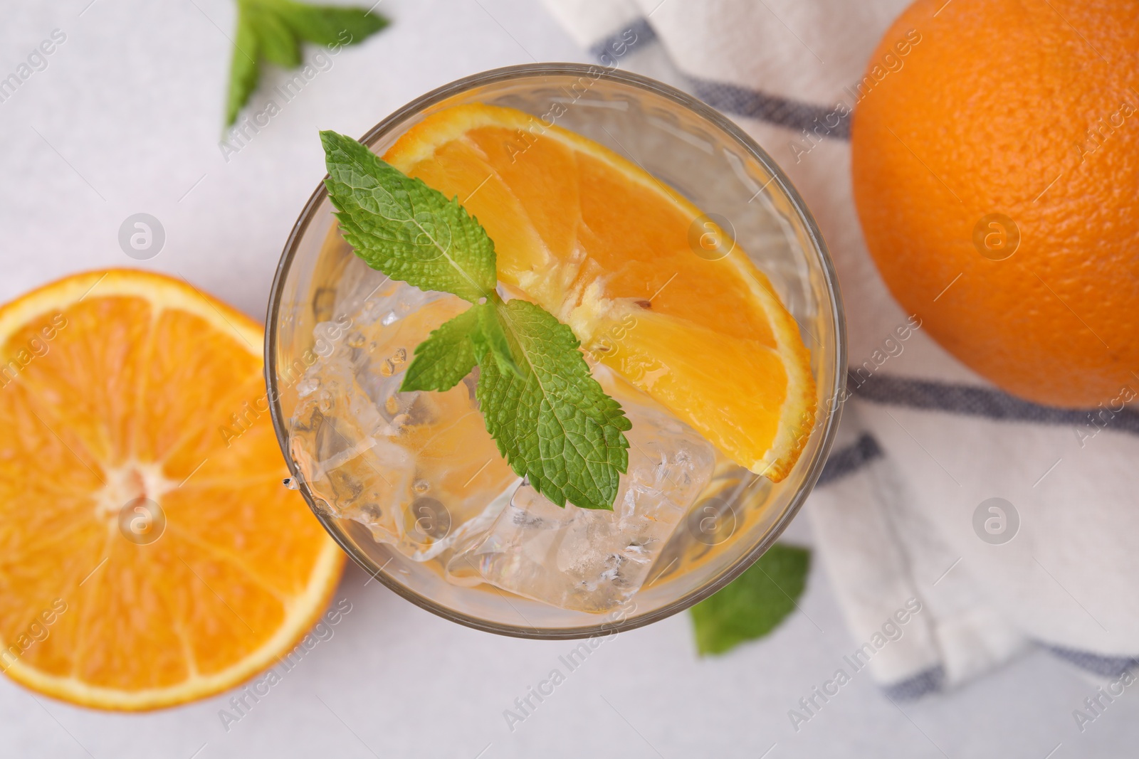 Photo of Refreshing water with orange and mint in glass on light table, flat lay