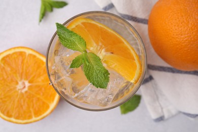 Refreshing water with orange and mint in glass on light table, flat lay