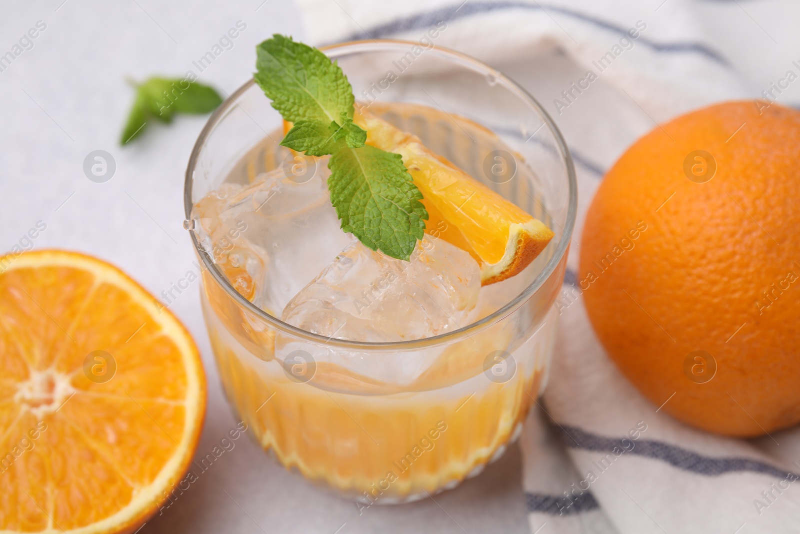 Photo of Refreshing water with orange and mint in glass on light table, closeup