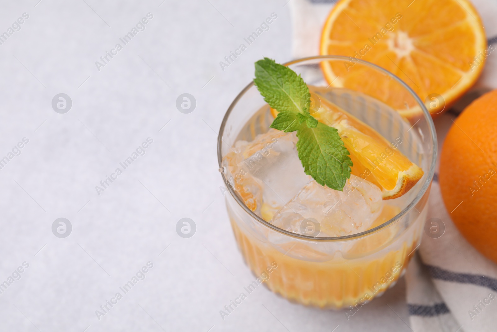 Photo of Refreshing water with orange and mint in glass on light table, closeup. Space for text