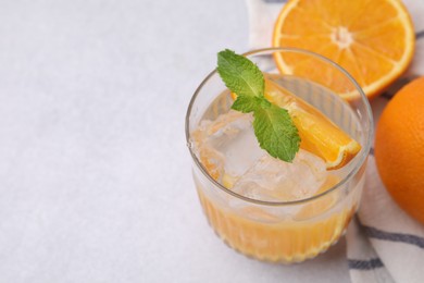 Photo of Refreshing water with orange and mint in glass on light table, closeup. Space for text