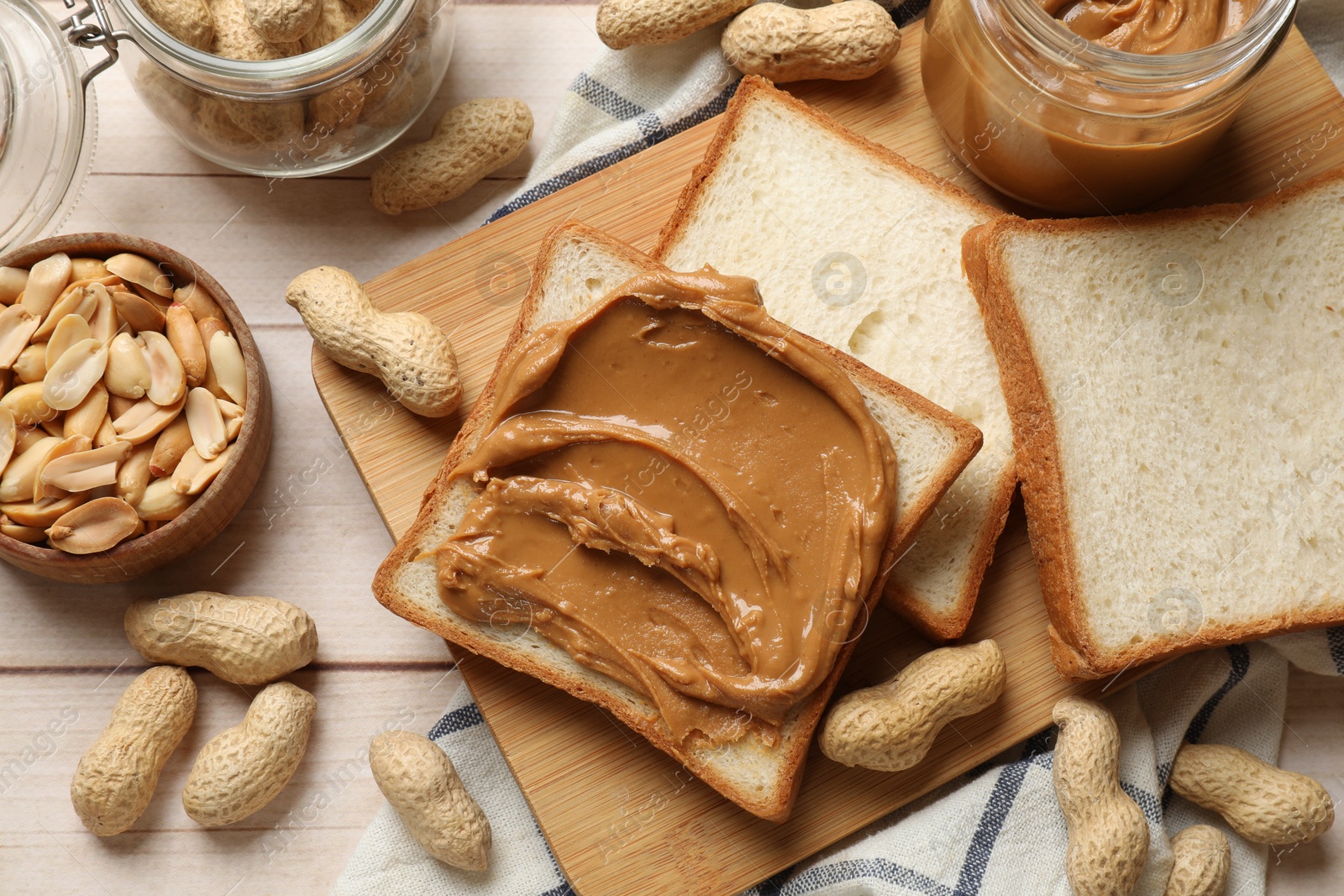 Photo of Delicious sandwich with peanut butter and nuts on white wooden table, flat lay