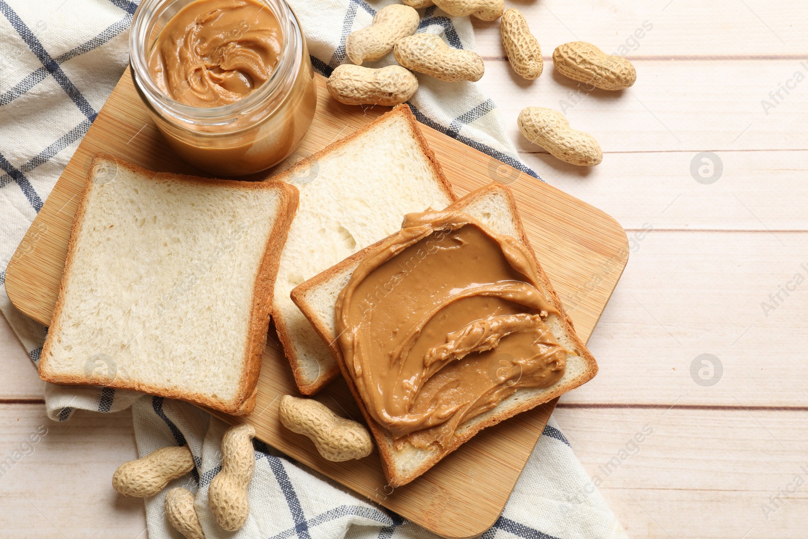 Photo of Delicious sandwich with peanut butter and nuts on white wooden table, flat lay