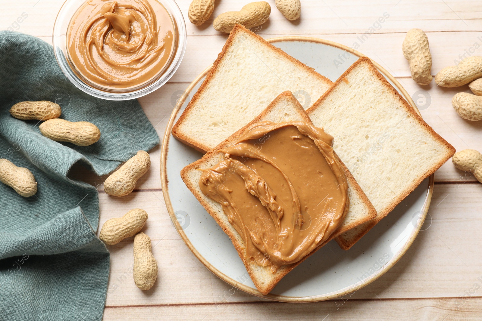 Photo of Delicious sandwich with peanut butter and nuts on white wooden table, flat lay