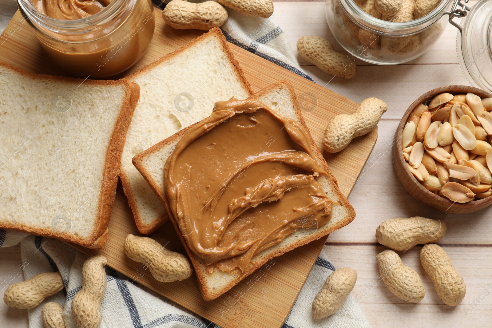 Photo of Delicious sandwich with peanut butter and nuts on white wooden table, flat lay