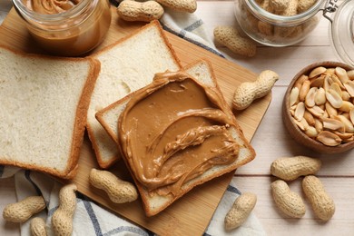 Delicious sandwich with peanut butter and nuts on white wooden table, flat lay