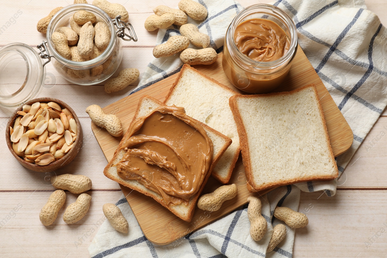 Photo of Delicious sandwich with peanut butter and nuts on white wooden table, flat lay