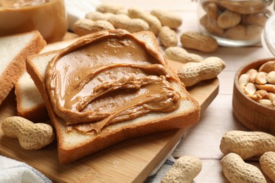 Delicious sandwich with peanut butter and nuts on white wooden table, closeup