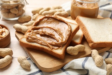 Photo of Delicious sandwich with peanut butter and nuts on white wooden table, closeup