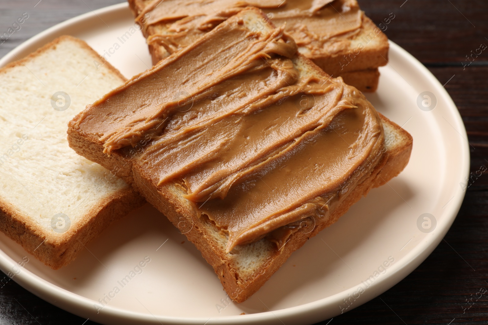 Photo of Delicious sandwiches with peanut butter on wooden table, closeup