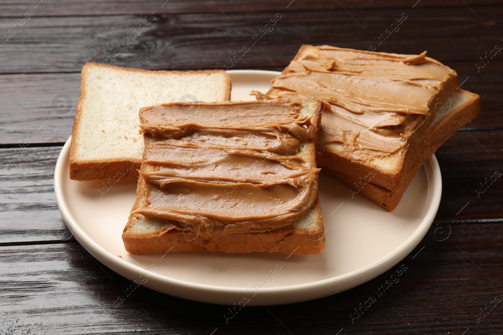 Photo of Delicious sandwiches with peanut butter on wooden table