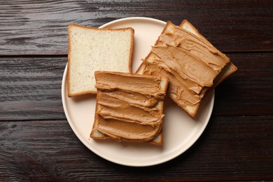 Photo of Delicious sandwiches with peanut butter on wooden table, top view