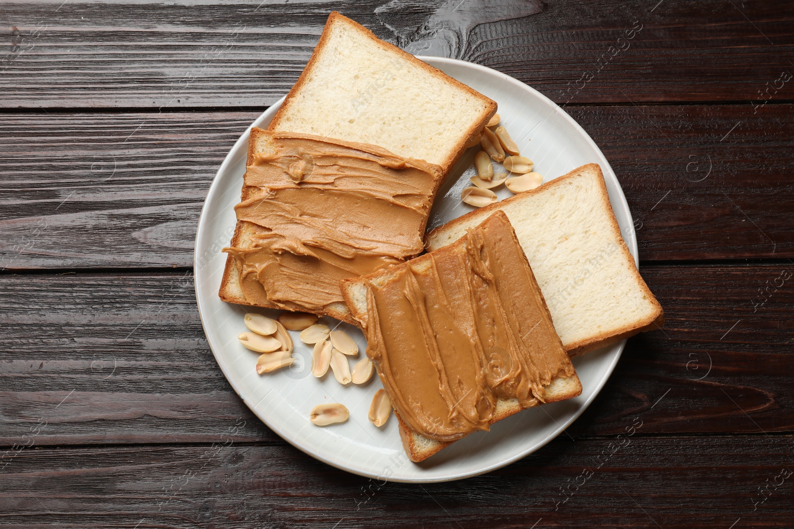 Photo of Delicious sandwiches with peanut butter and nuts on wooden table, top view