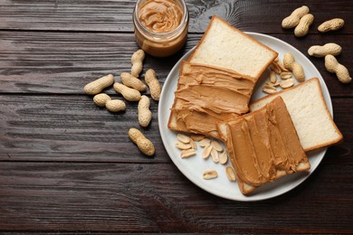 Photo of Delicious sandwiches with peanut butter and nuts on wooden table, flat lay