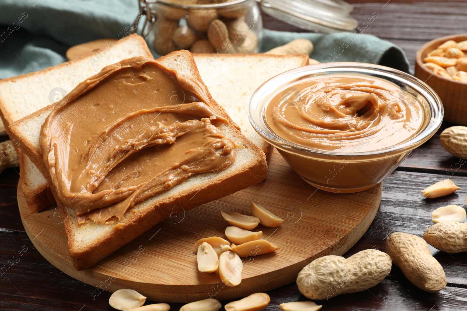 Photo of Delicious sandwich with peanut butter and nuts on wooden table, closeup