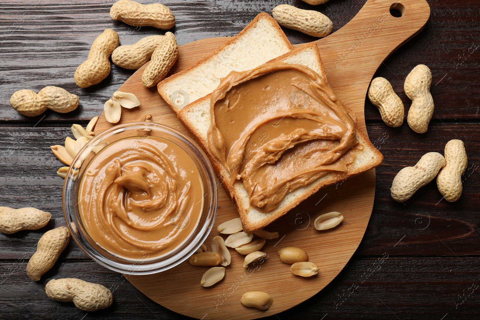 Photo of Delicious sandwich with peanut butter and nuts on wooden table, flat lay