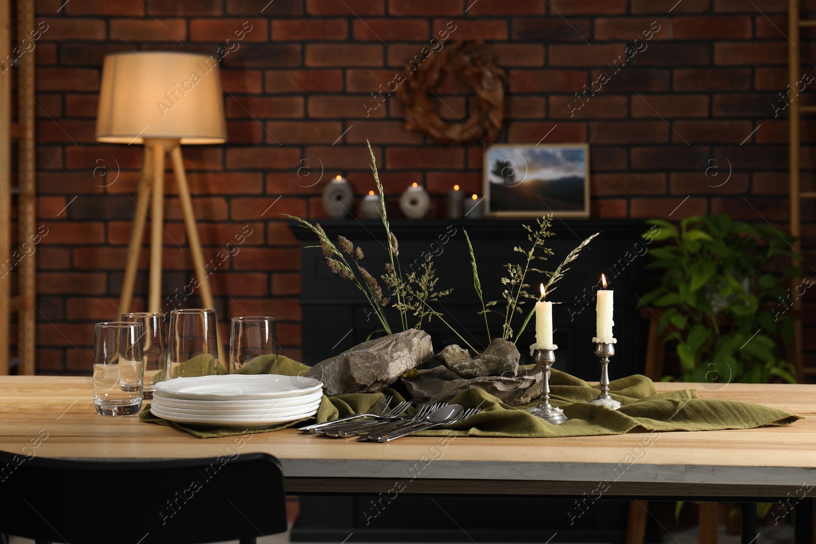 Photo of Clean dishes, stones and plants on wooden table in stylish dining room