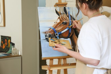 Photo of Woman drawing cute horse with brush in studio