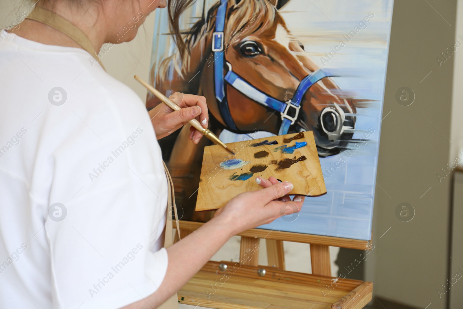 Photo of Woman drawing cute horse with brush in studio, closeup