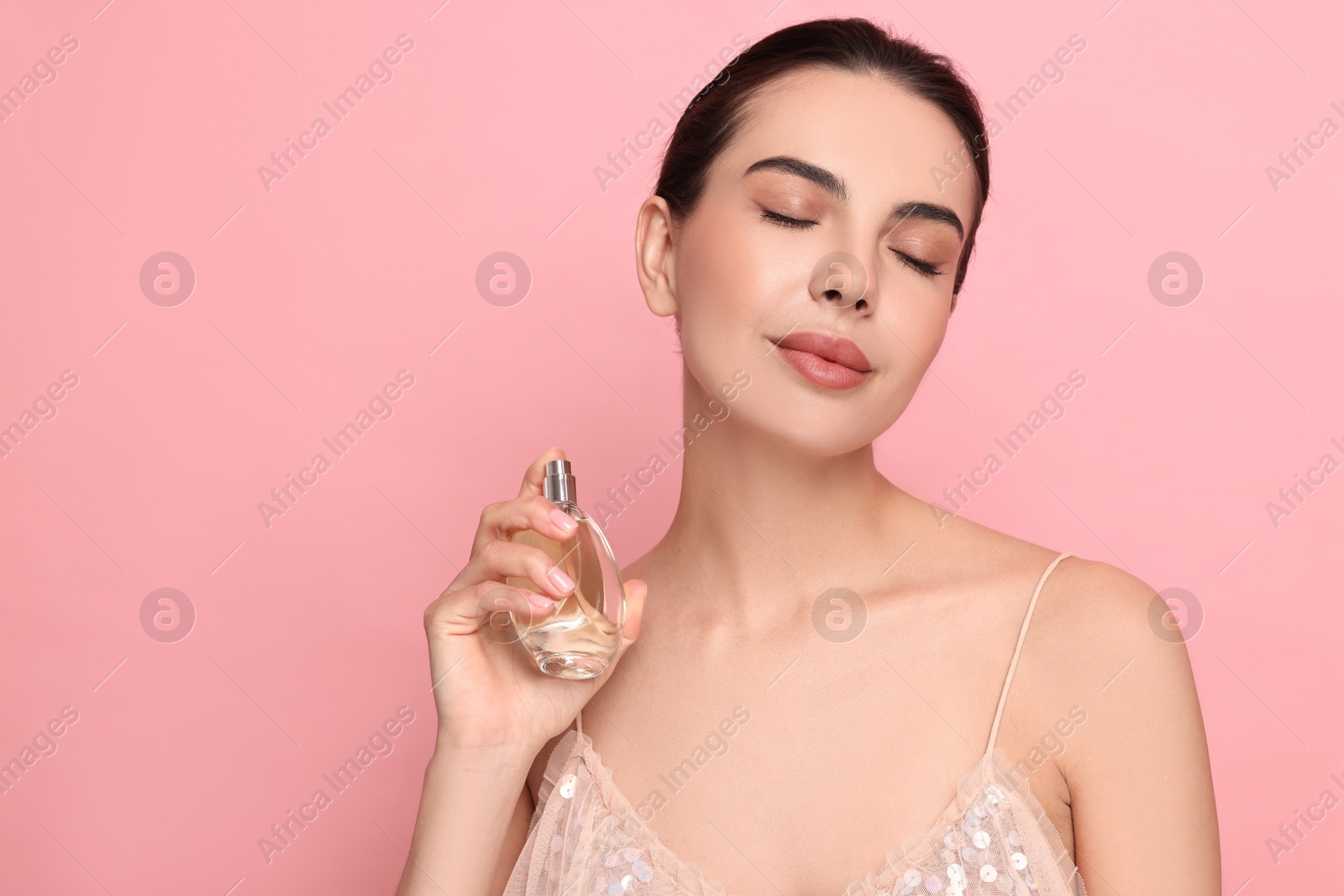 Photo of Beautiful woman with bottle of perfume on pink background. Space for text