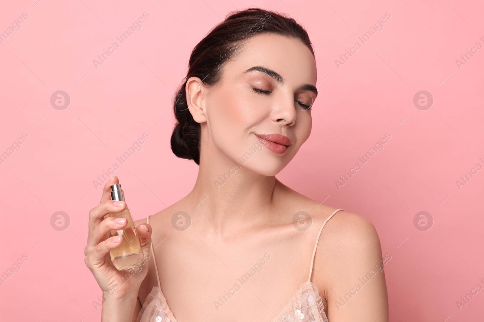 Photo of Beautiful woman with bottle of perfume on pink background