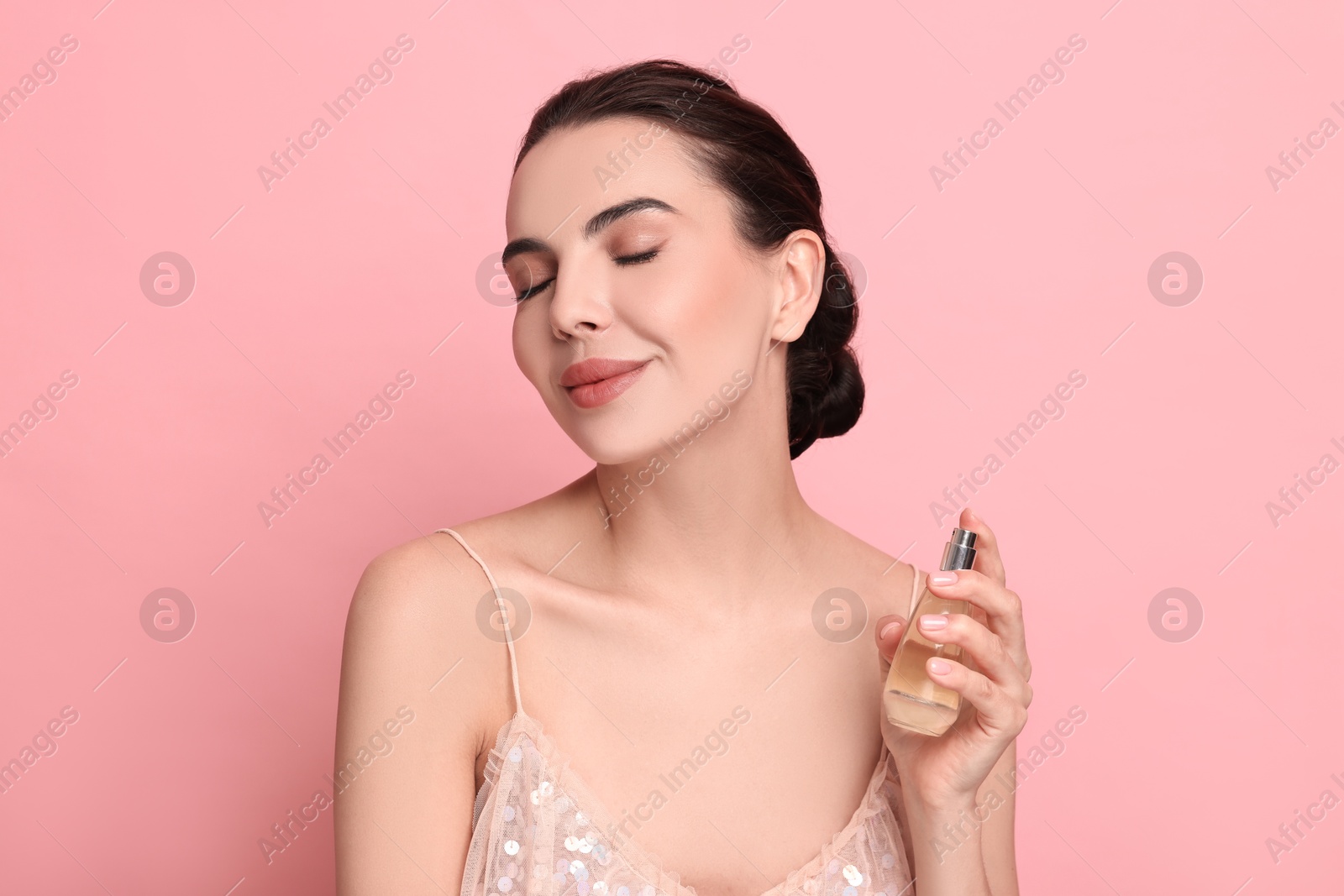 Photo of Beautiful woman with bottle of perfume on pink background