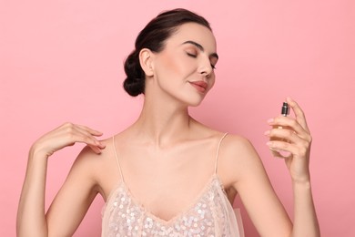 Beautiful woman with bottle of perfume on pink background