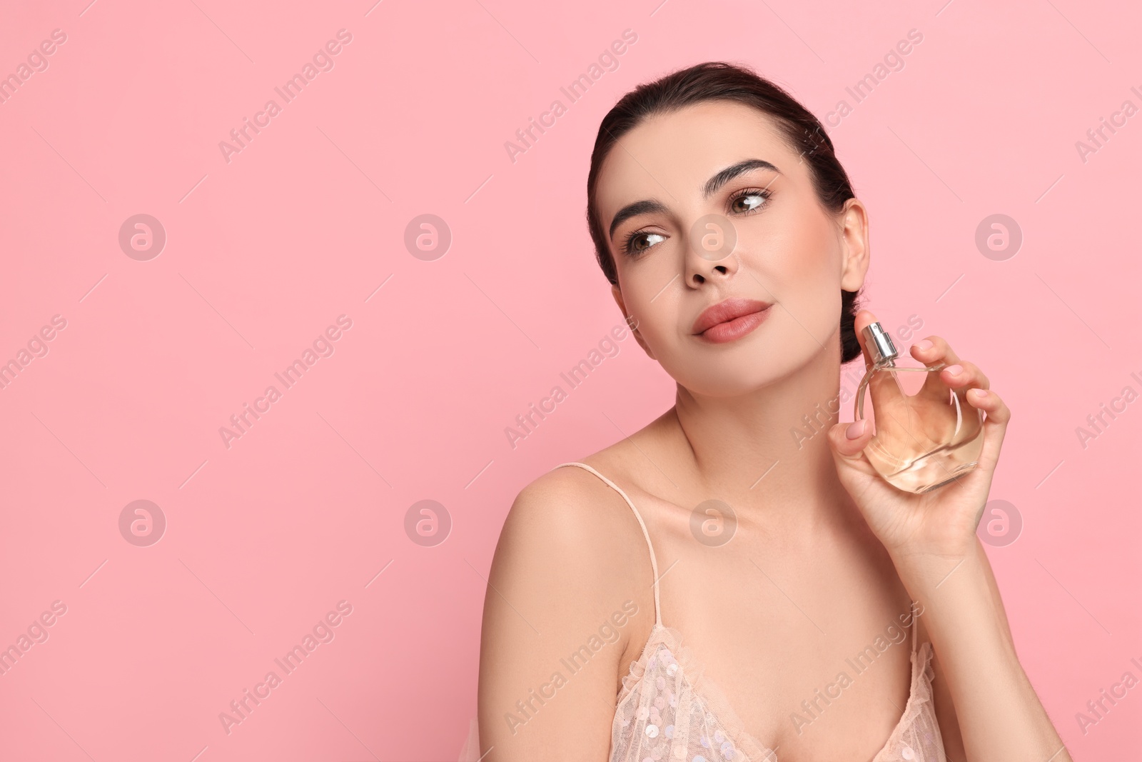 Photo of Beautiful woman with bottle of perfume on pink background. Space for text