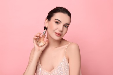 Photo of Beautiful woman with bottle of perfume on pink background