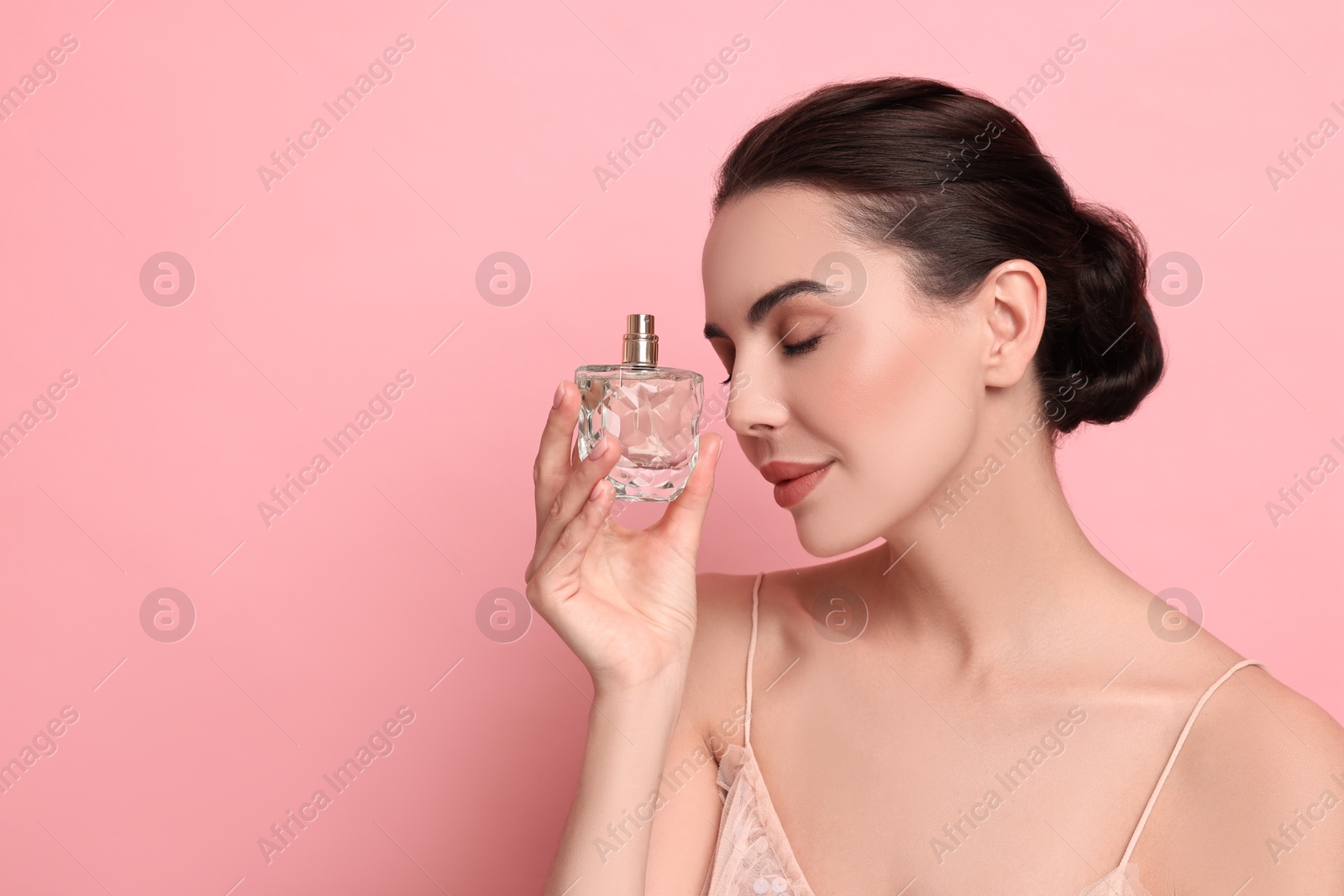 Photo of Beautiful woman with bottle of perfume on pink background. Space for text