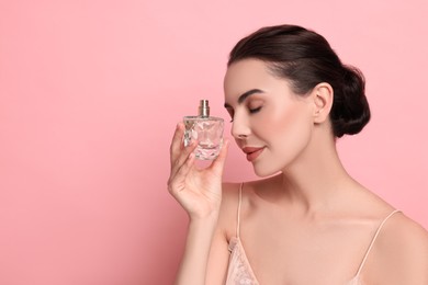 Photo of Beautiful woman with bottle of perfume on pink background. Space for text