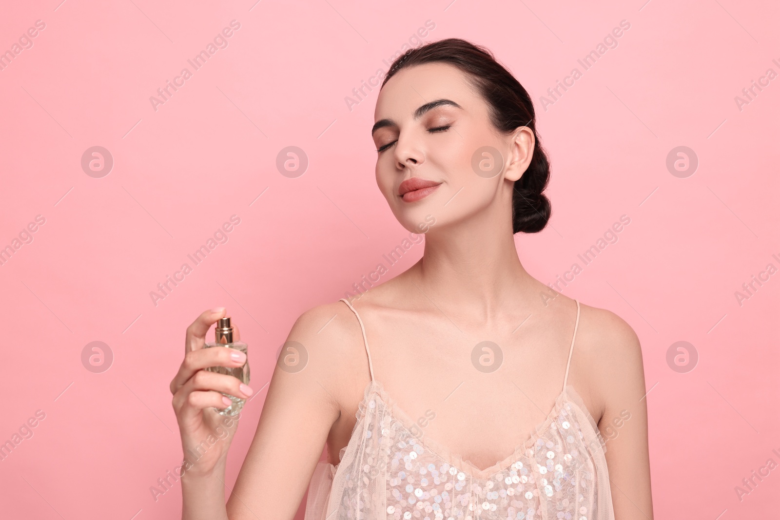 Photo of Beautiful woman spraying perfume on pink background