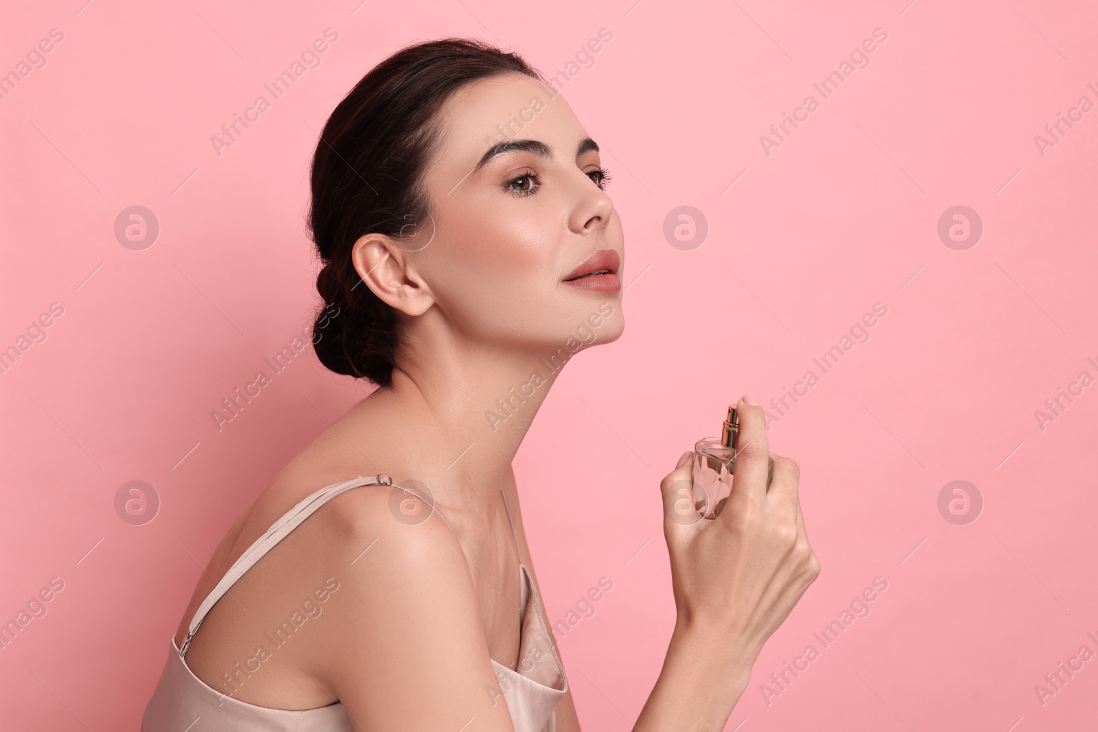 Photo of Beautiful woman with bottle of perfume on pink background