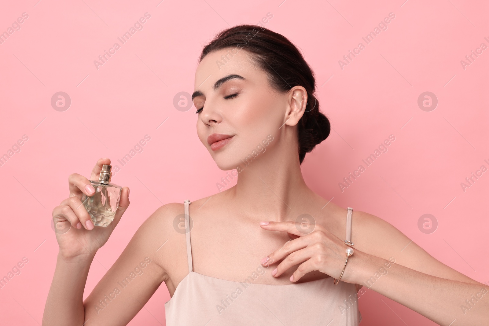 Photo of Beautiful woman with bottle of perfume on pink background