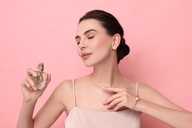 Beautiful woman with bottle of perfume on pink background