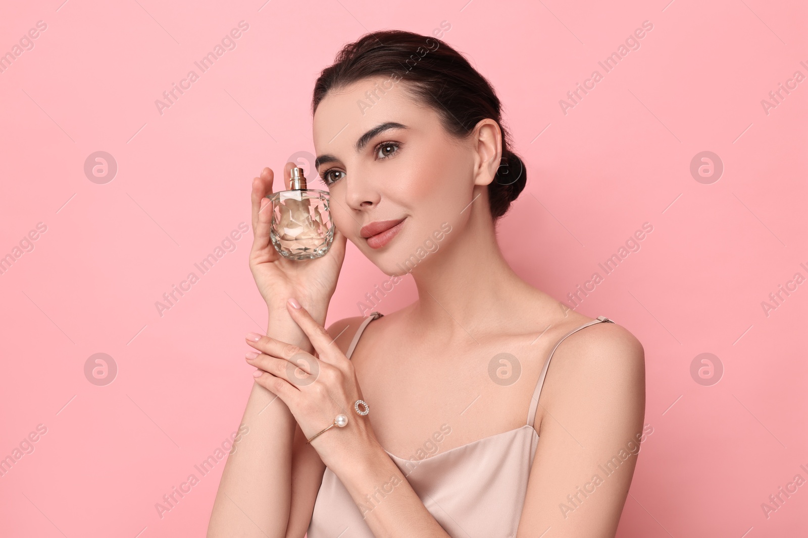 Photo of Beautiful woman with bottle of perfume on pink background