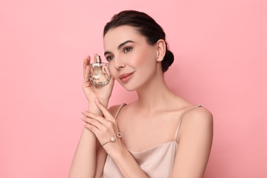 Photo of Beautiful woman with bottle of perfume on pink background