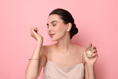 Photo of Beautiful woman smelling perfume on pink background