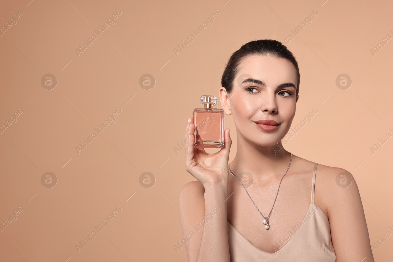 Photo of Beautiful woman with bottle of perfume on beige background. Space for text