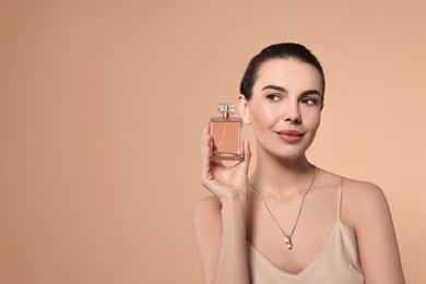 Photo of Beautiful woman with bottle of perfume on beige background. Space for text