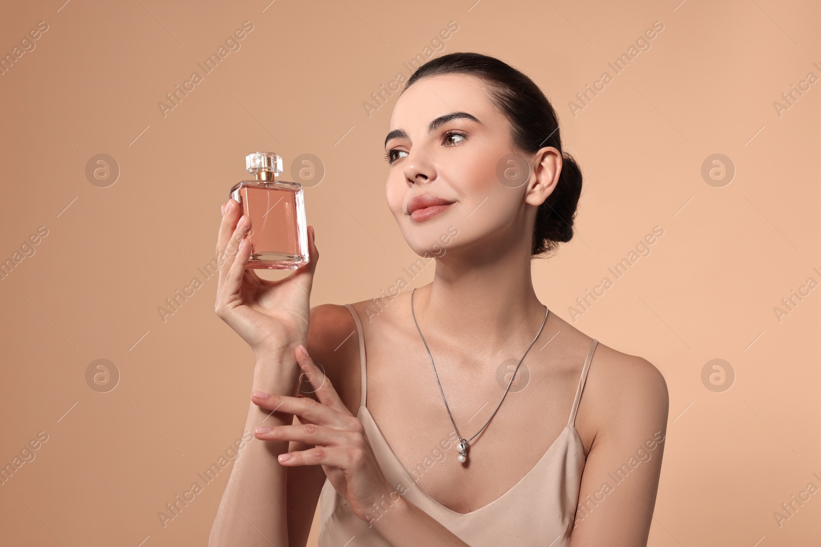 Photo of Beautiful woman with bottle of perfume on beige background