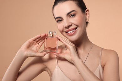 Photo of Smiling woman with bottle of perfume on beige background