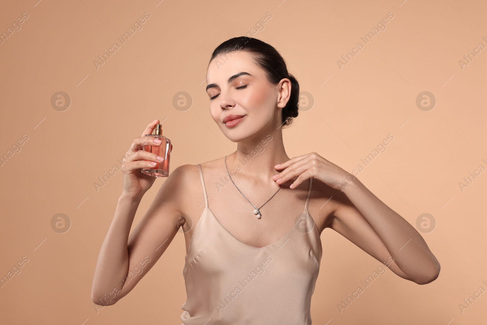 Photo of Beautiful woman with bottle of perfume on beige background