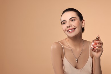 Photo of Smiling woman with bottle of perfume on beige background. Space for text