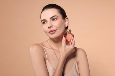 Photo of Beautiful woman with bottle of perfume on beige background