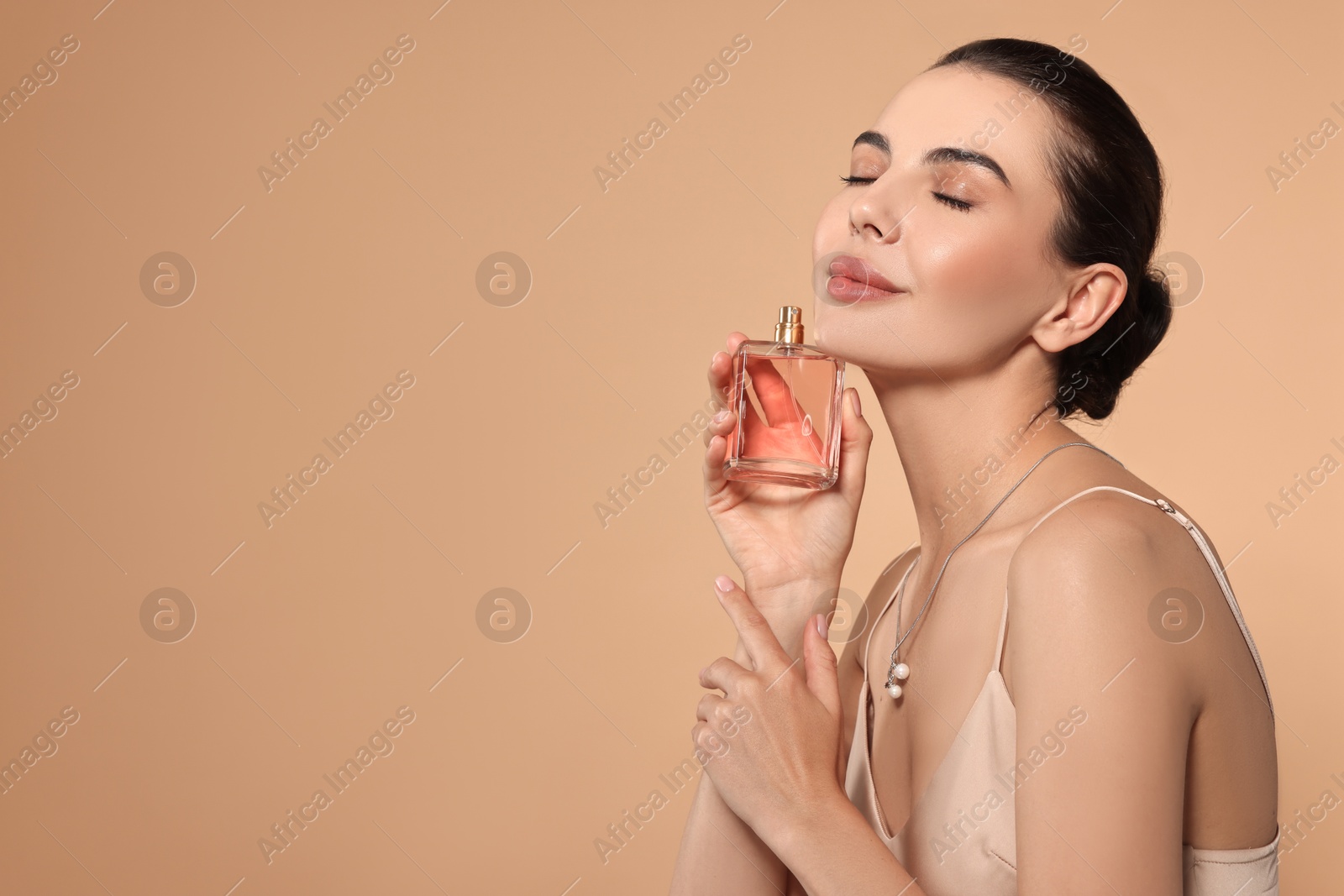 Photo of Beautiful woman with bottle of perfume on beige background. Space for text