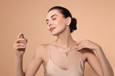 Beautiful woman with bottle of perfume on beige background