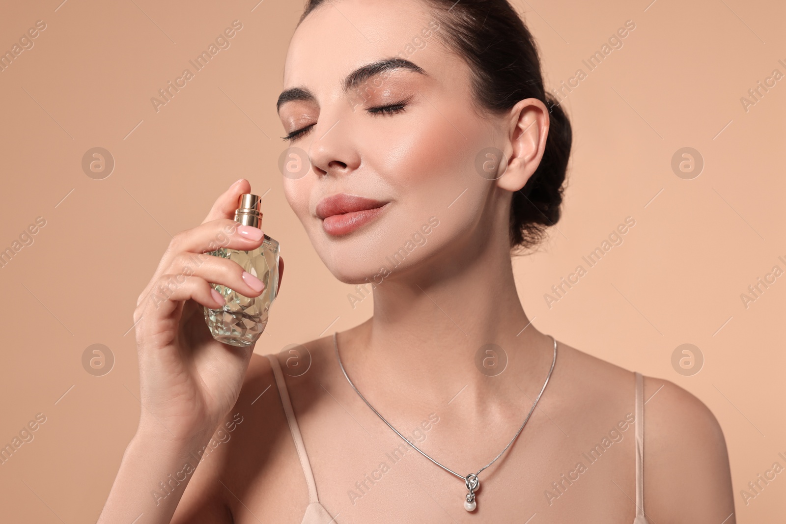 Photo of Beautiful woman with bottle of perfume on beige background