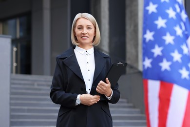 International relations. Diplomat with clipboard near flag of USA outdoors